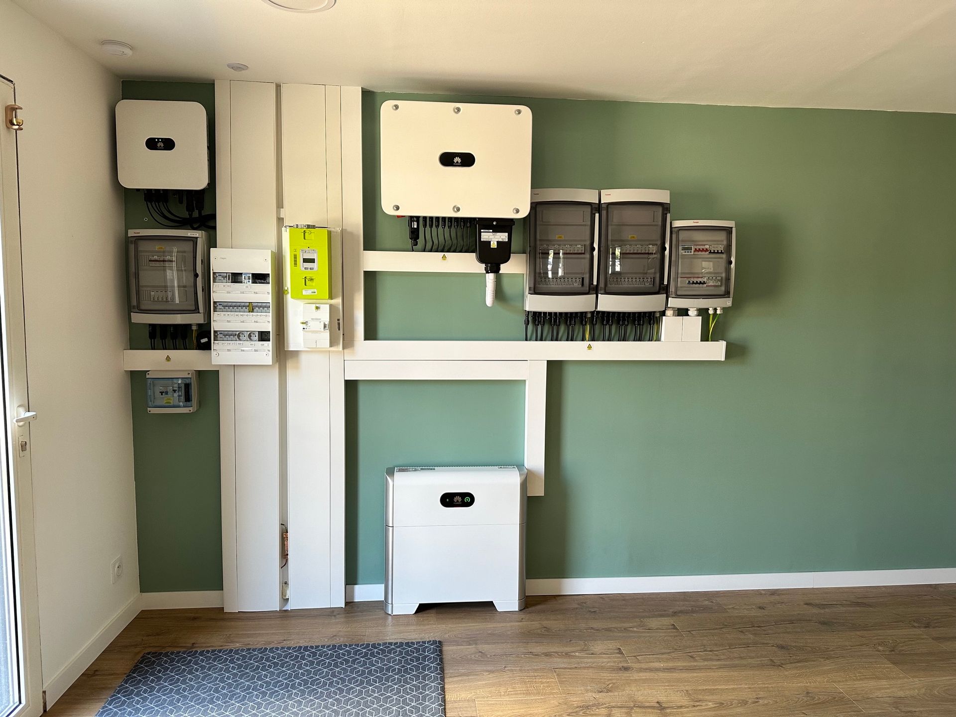 Système d'énergie solaire avec onduleurs muraux blancs, unité de batterie et boîtes de disjoncteurs électriques sur un mur vert