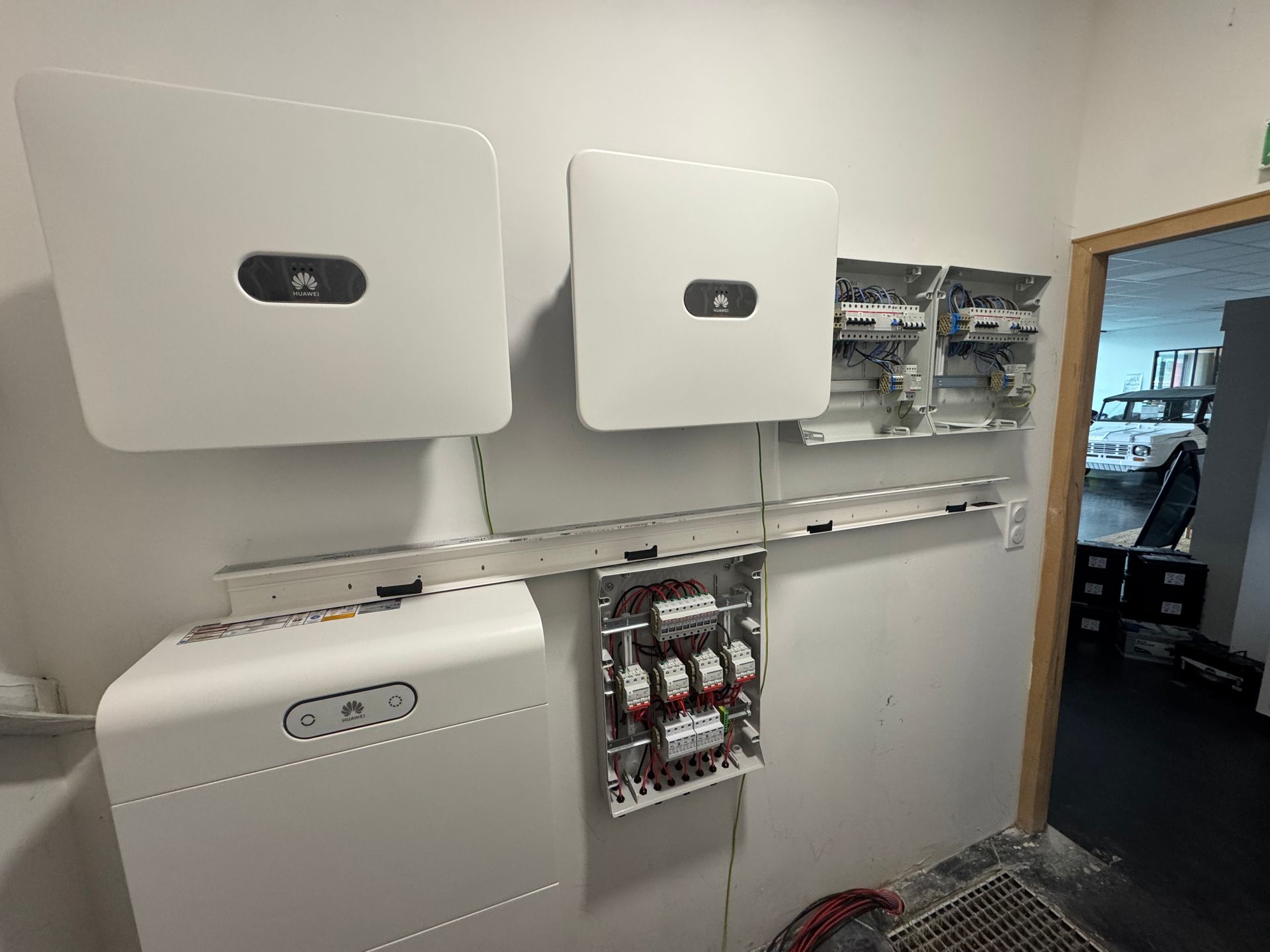 Système d'onduleur solaire mural et de batterie avec boîtes de distribution électrique apparentes dans un intérieur aux murs blancs