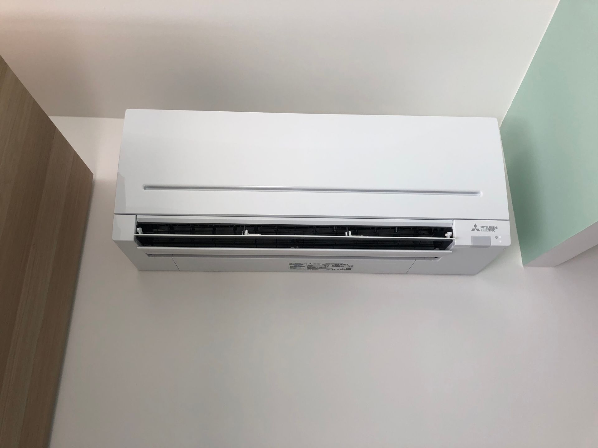 Un climatiseur mural Mitsubishi blanc, installé sur un mur blanc