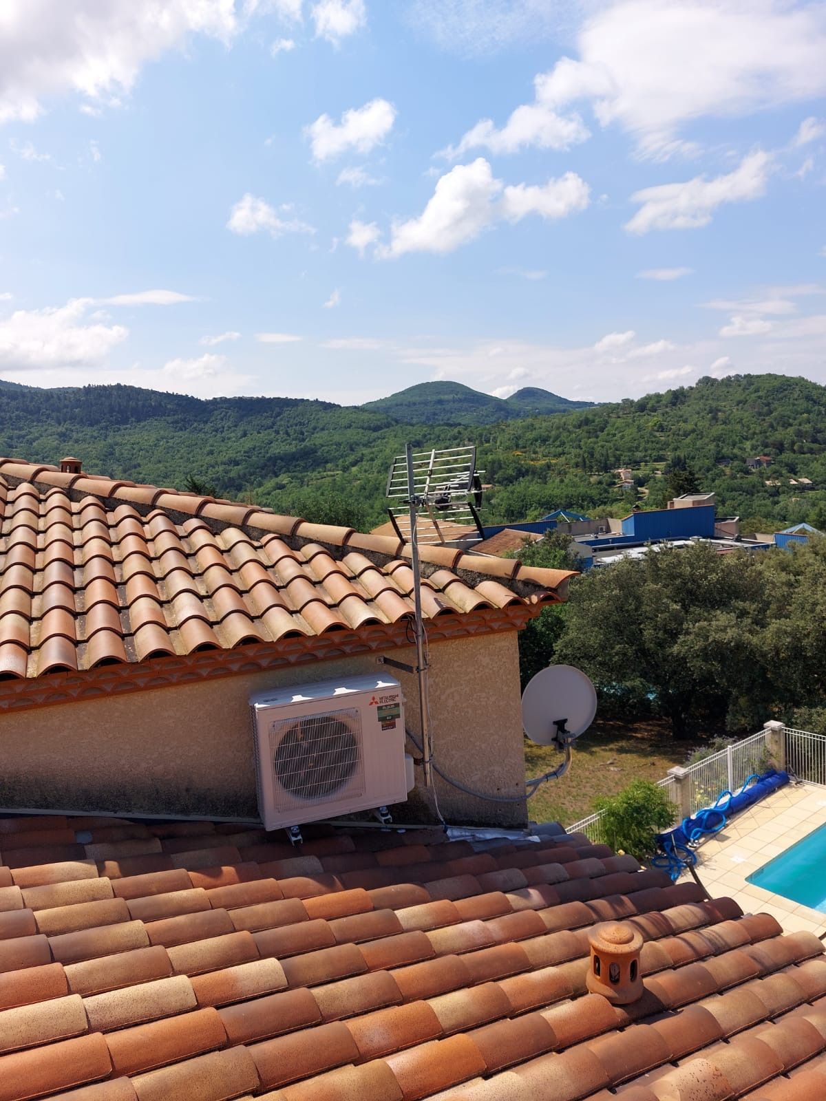 Toit de tuiles, unité de climatisation, antenne de télévision, parabole et piscine en contrebas