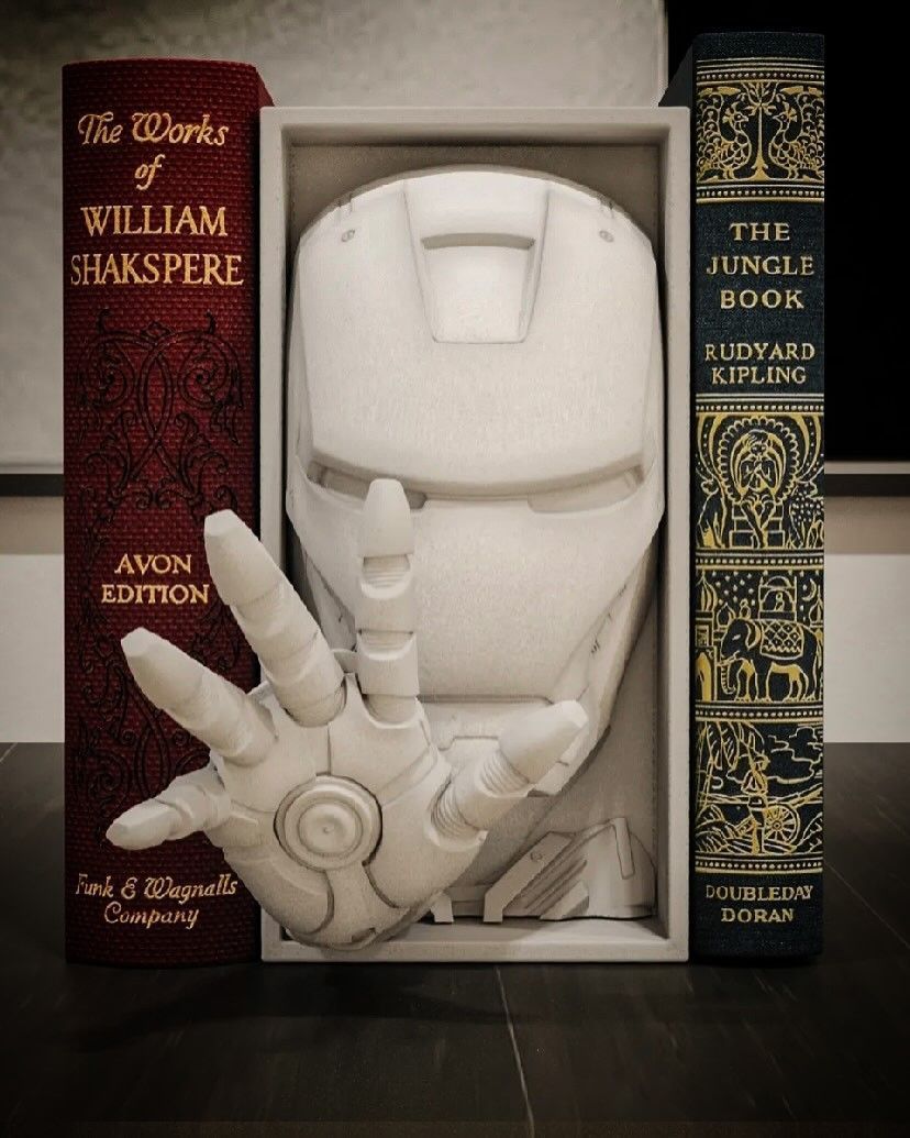 Escultura de casco y mano de Iron Man enmarcada por volúmenes de Shakespeare y El libro de la selva.