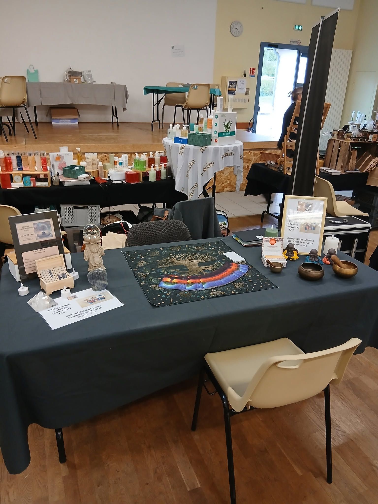Table de vendeur dans un marché couvert, proposant des articles artisanaux, des livres et des poteries sur une nappe noire