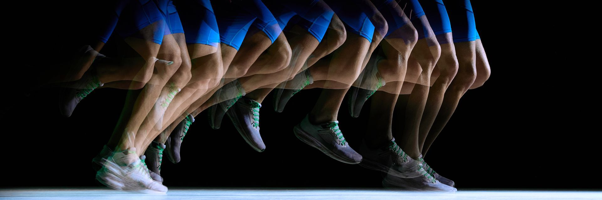 Séquence floue d'un coureur sprintant en bleu et beige sur fond noir