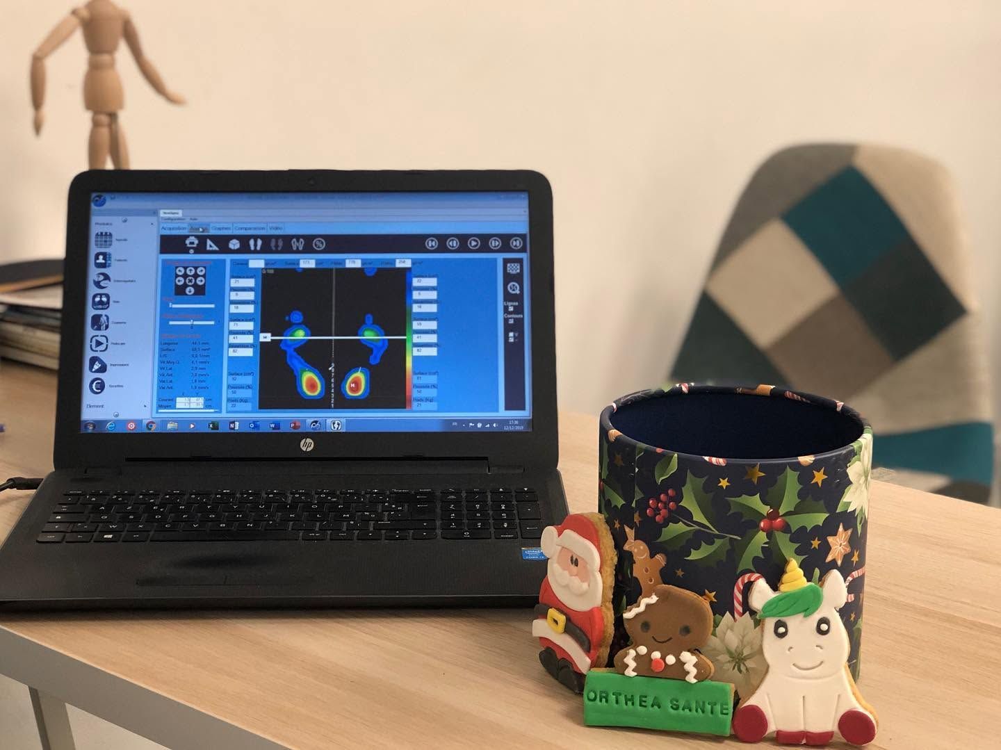 Un ordinateur portable sur un bureau, une tasse colorée et une décoration dans un espace de travail confortable