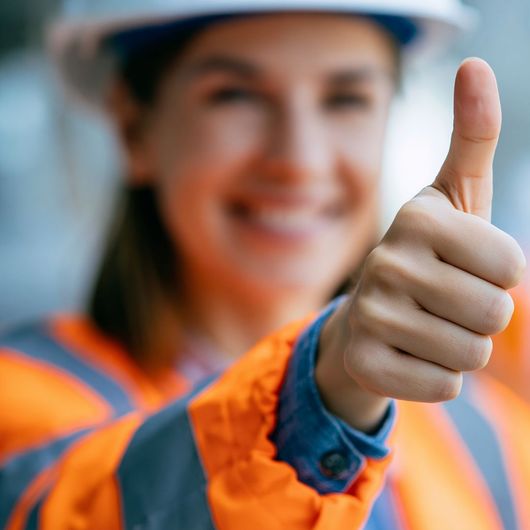 Ouvrier du bâtiment en tenue de sécurité orange faisant un signe d'approbation