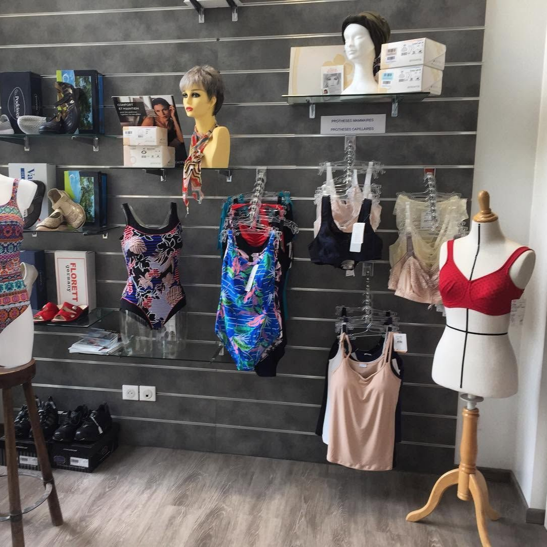 Présentoir de maillots de bain colorés, des mannequins et des étagères sur un mur gris.