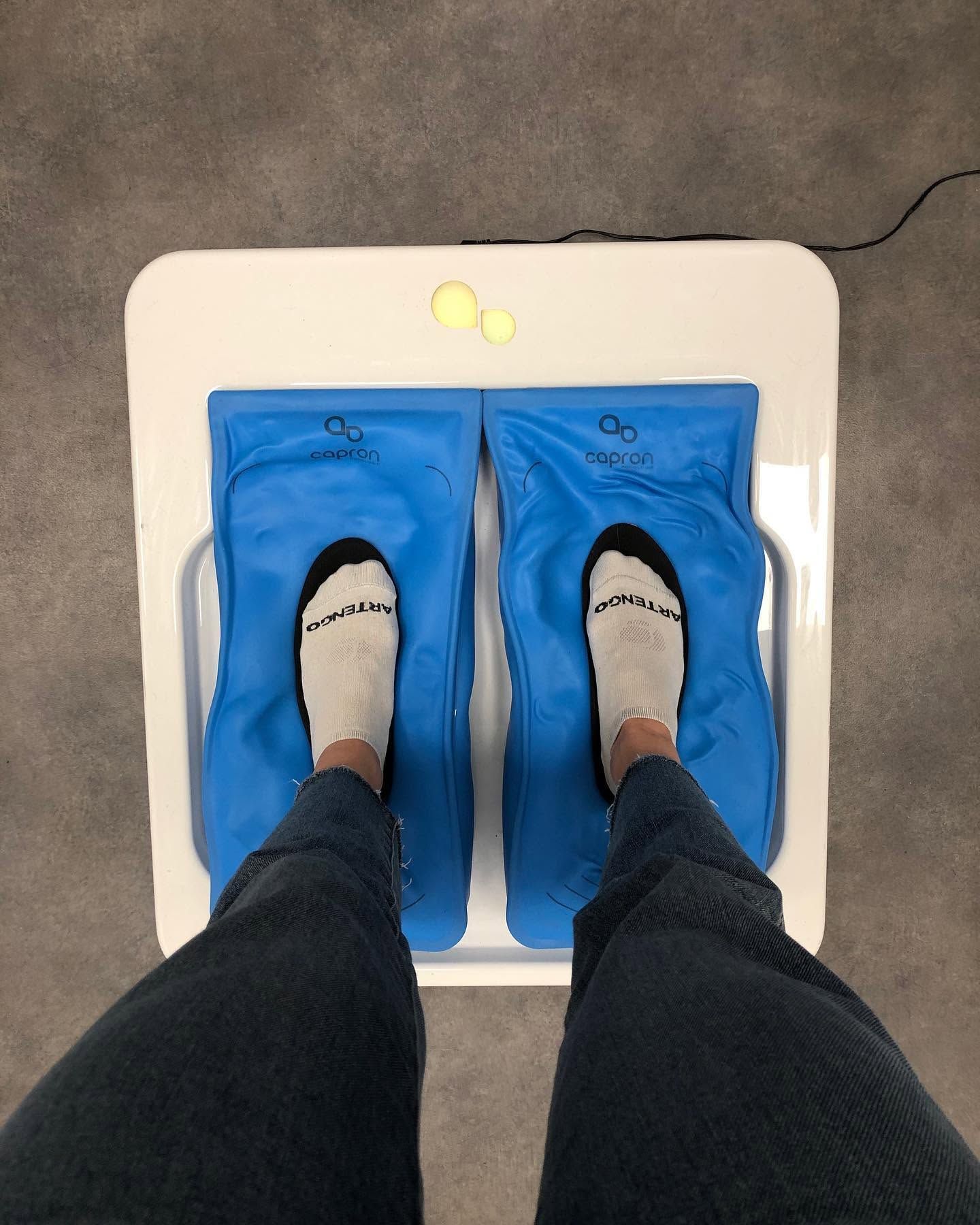 Une personne se tient debout sur une machine de thermoformage avec coussins pour la prise d'empreinte podologique