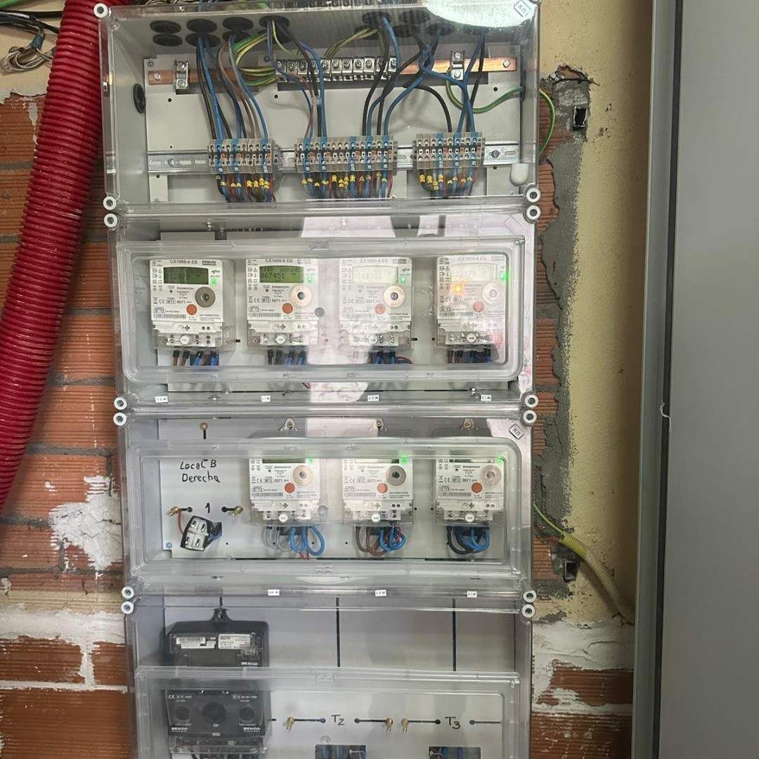 Panel de interruptores eléctricos con tapa transparente abierta y cableado visible en un hueco de la pared.