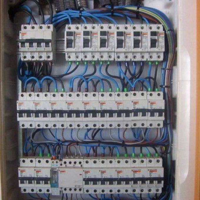 Panel de distribución eléctrica con filas de disyuntores y cableado azul.