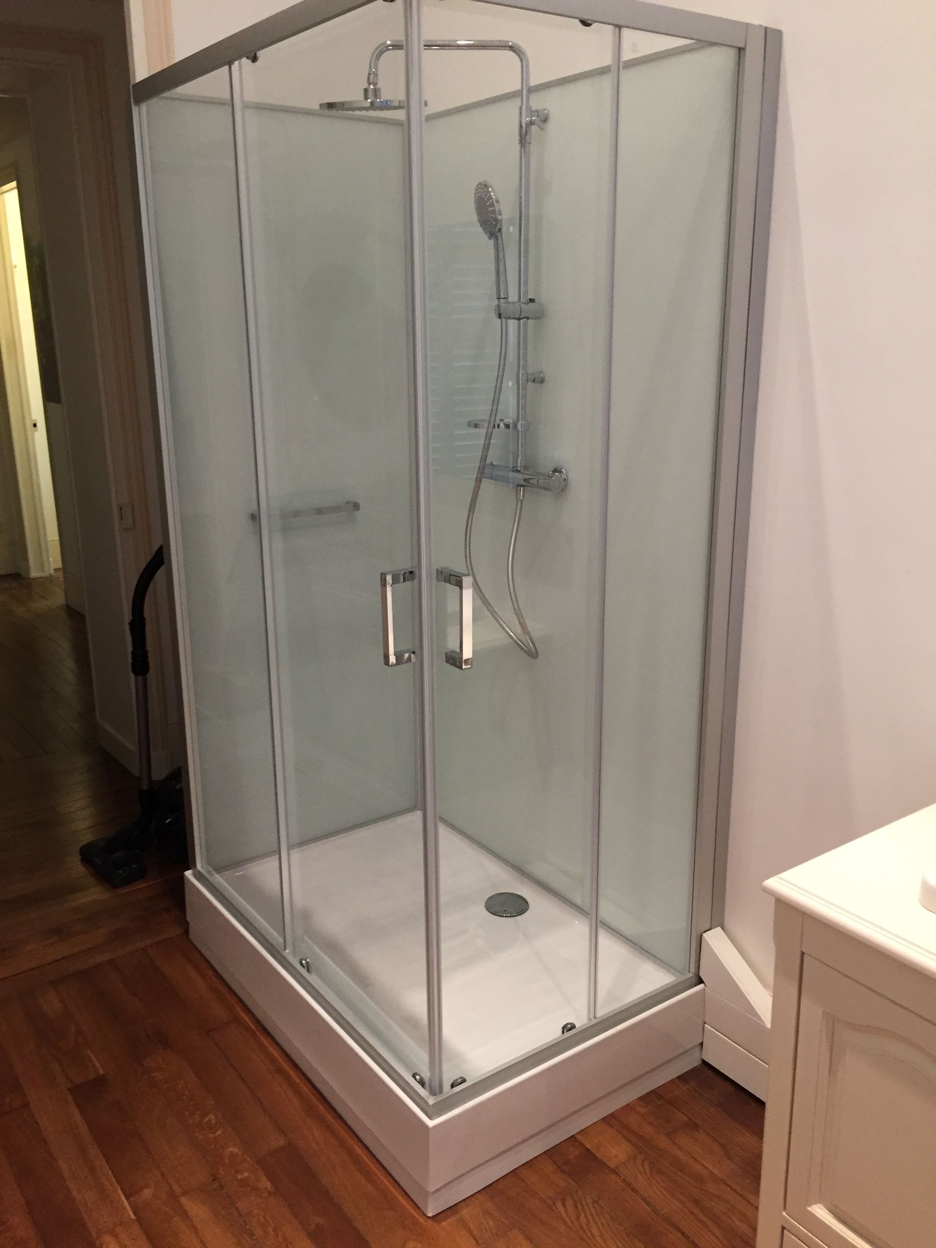 Cabine de douche installée avec parois vitrées et portes coulissantes