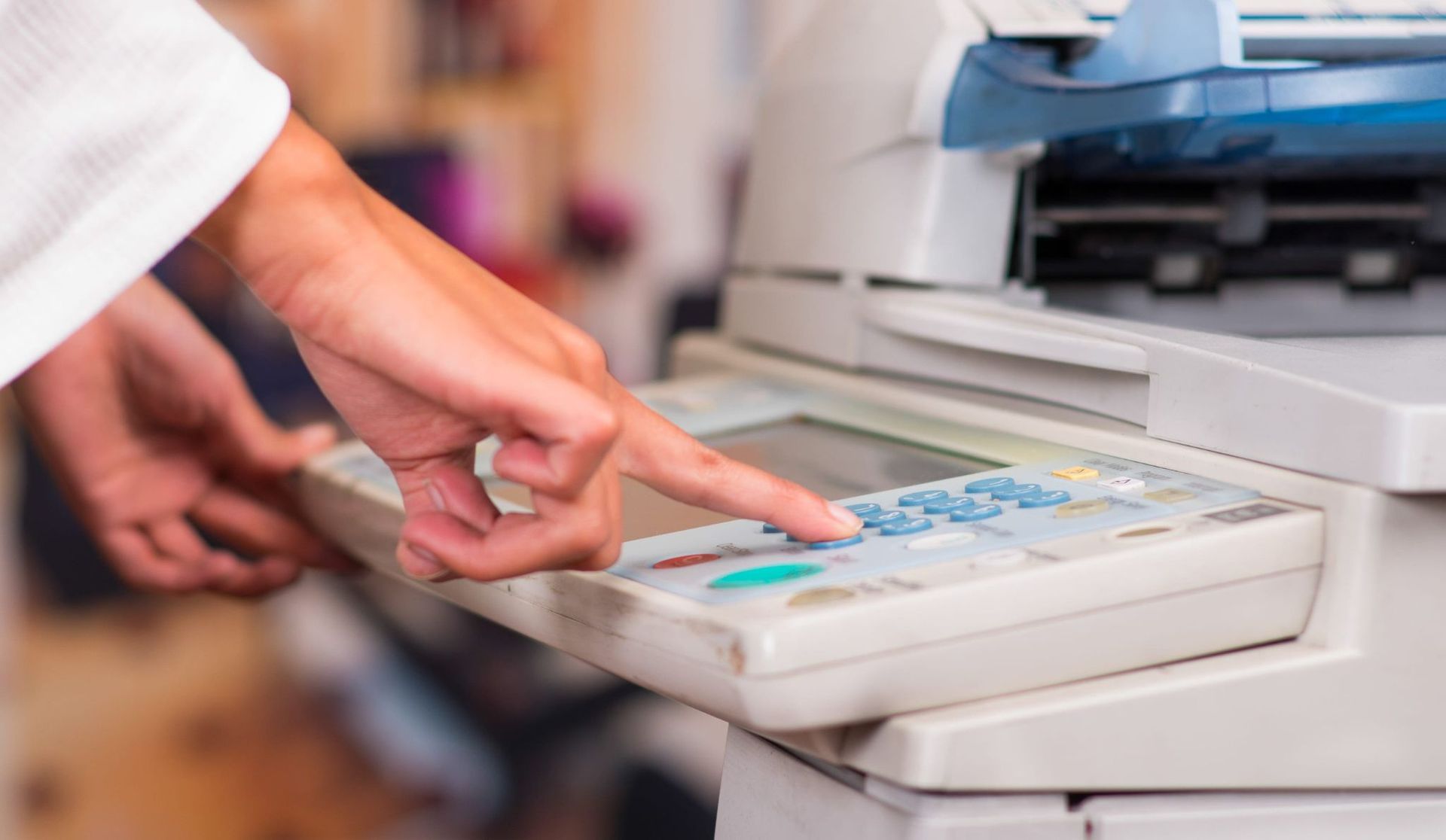 Una mano pulsando un botón en un dispositivo médico junto a una impresora o fotocopiadora.