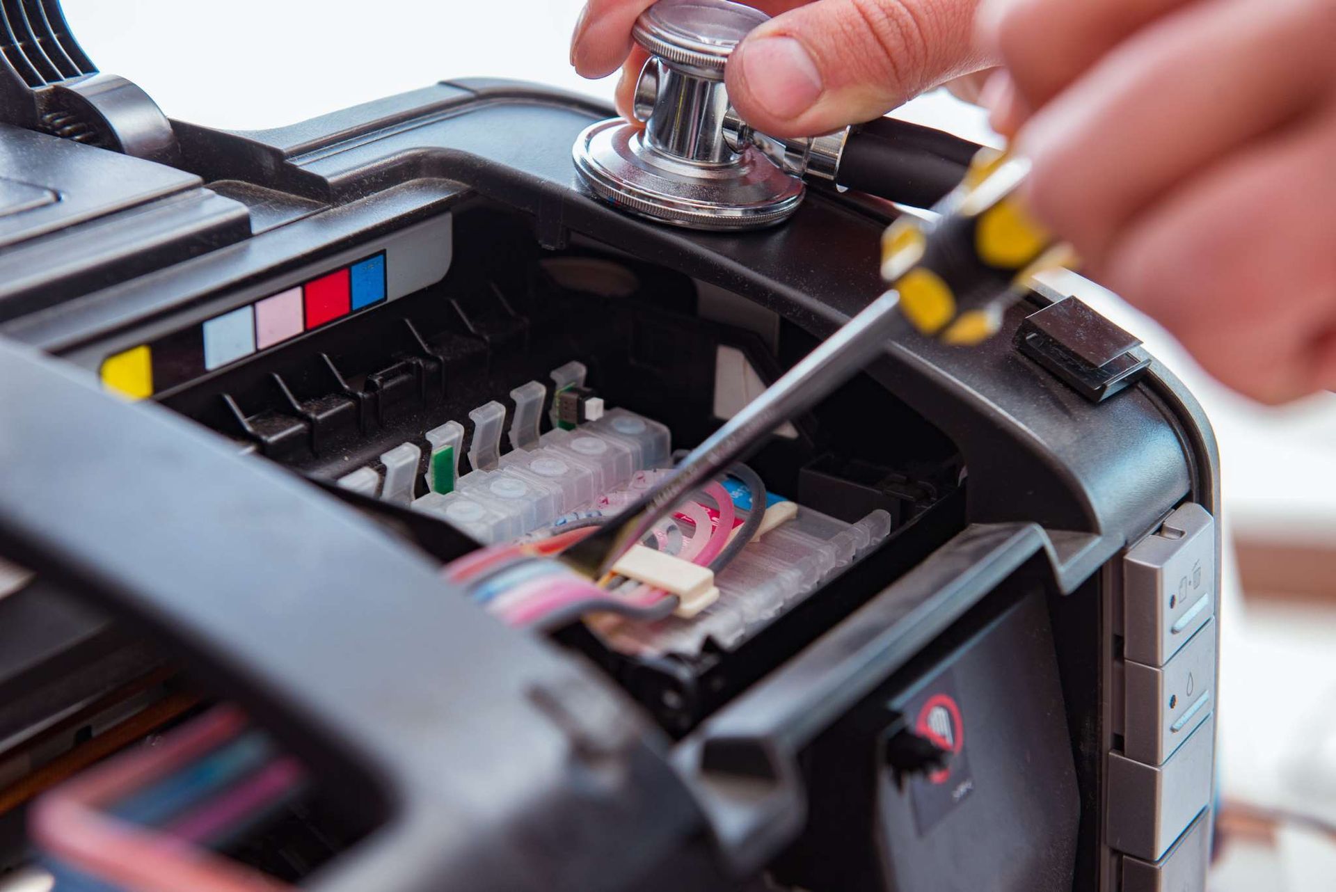 Una mano utiliza un destornillador para reparar el compartimento abierto de un pequeño dispositivo electrónico negro.