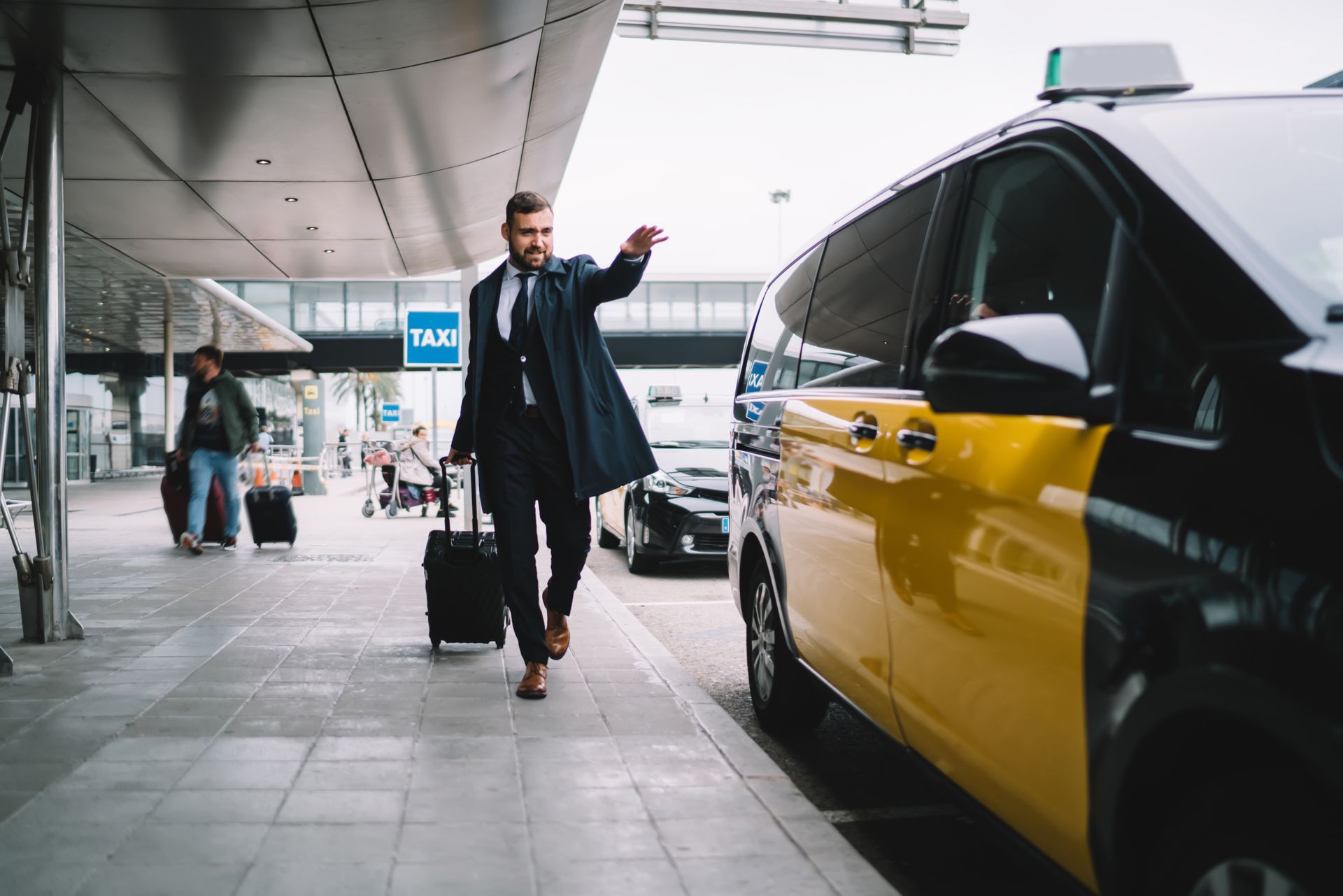Ein Mann mit einem Koffer geht auf ein Taxi zu.