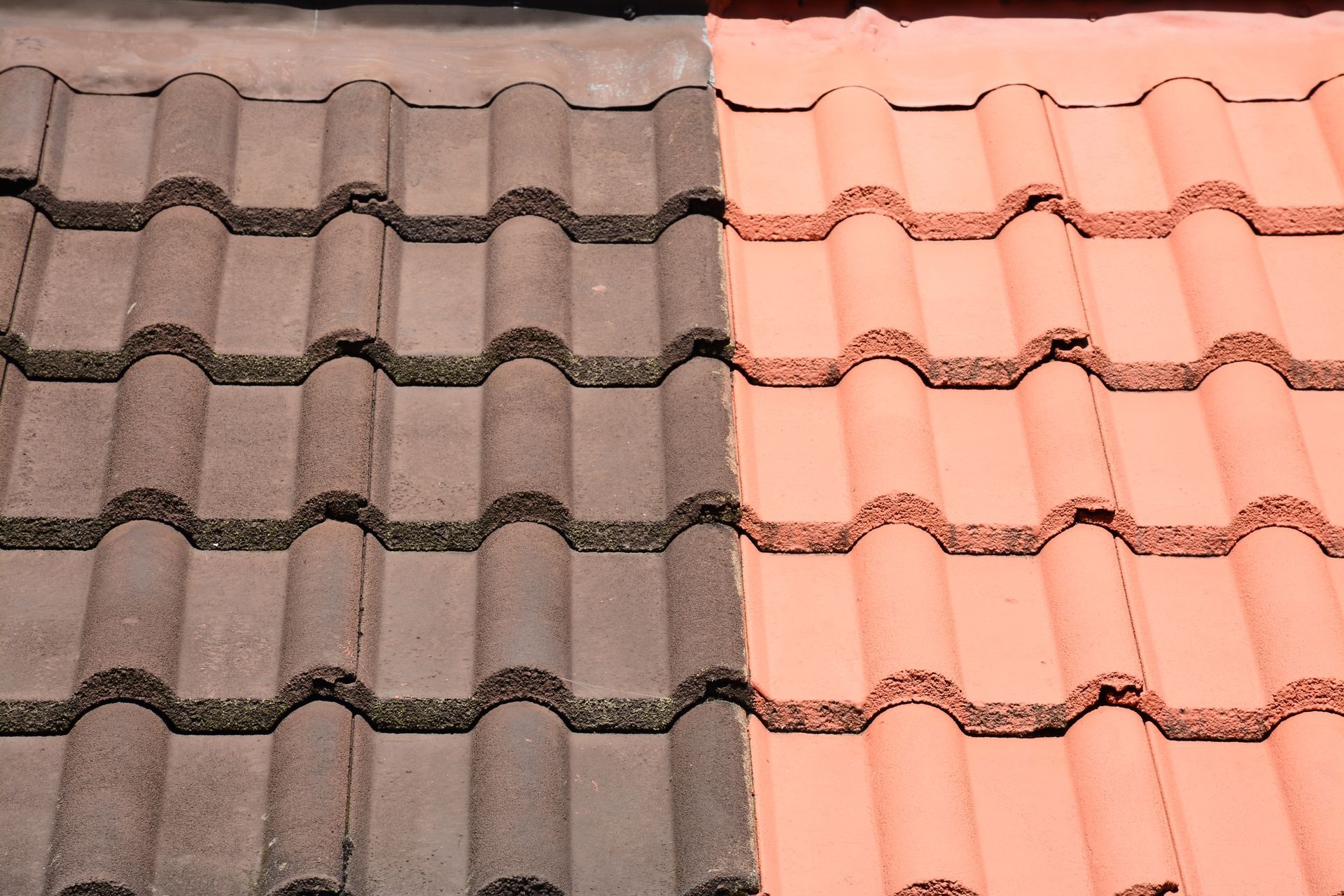 Tuiles de toit brunes, à moitié nettoyées, révélant leur couleur orange d'origine.