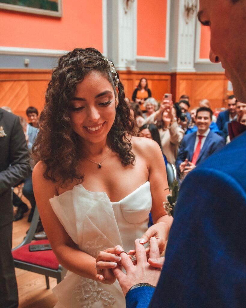 La mariée sourit tandis que le marié place la bague à son doigt pendant la cérémonie de mariage.