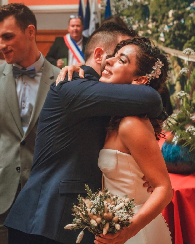 Les mariés s'embrassent, célébrant leur mariage. La femme est en robe blanche, l'homme en costume.