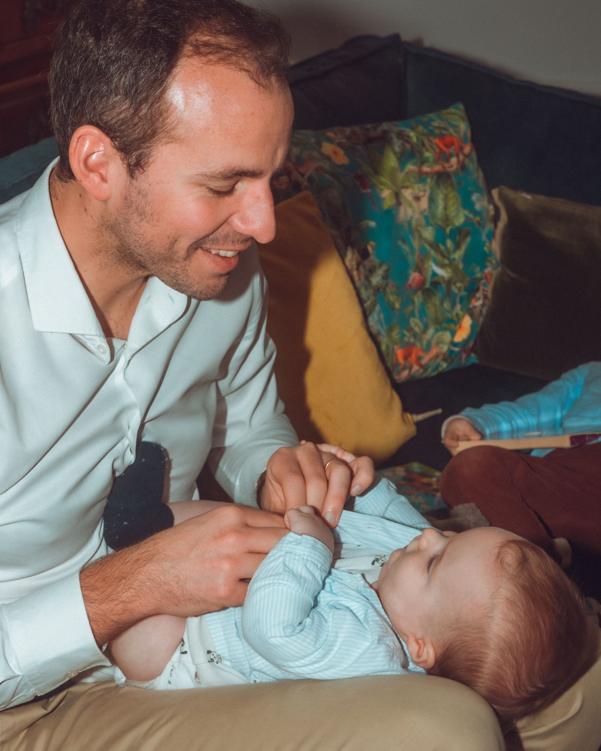 L'homme sourit au bébé sur ses genoux ; ils jouent ensemble.