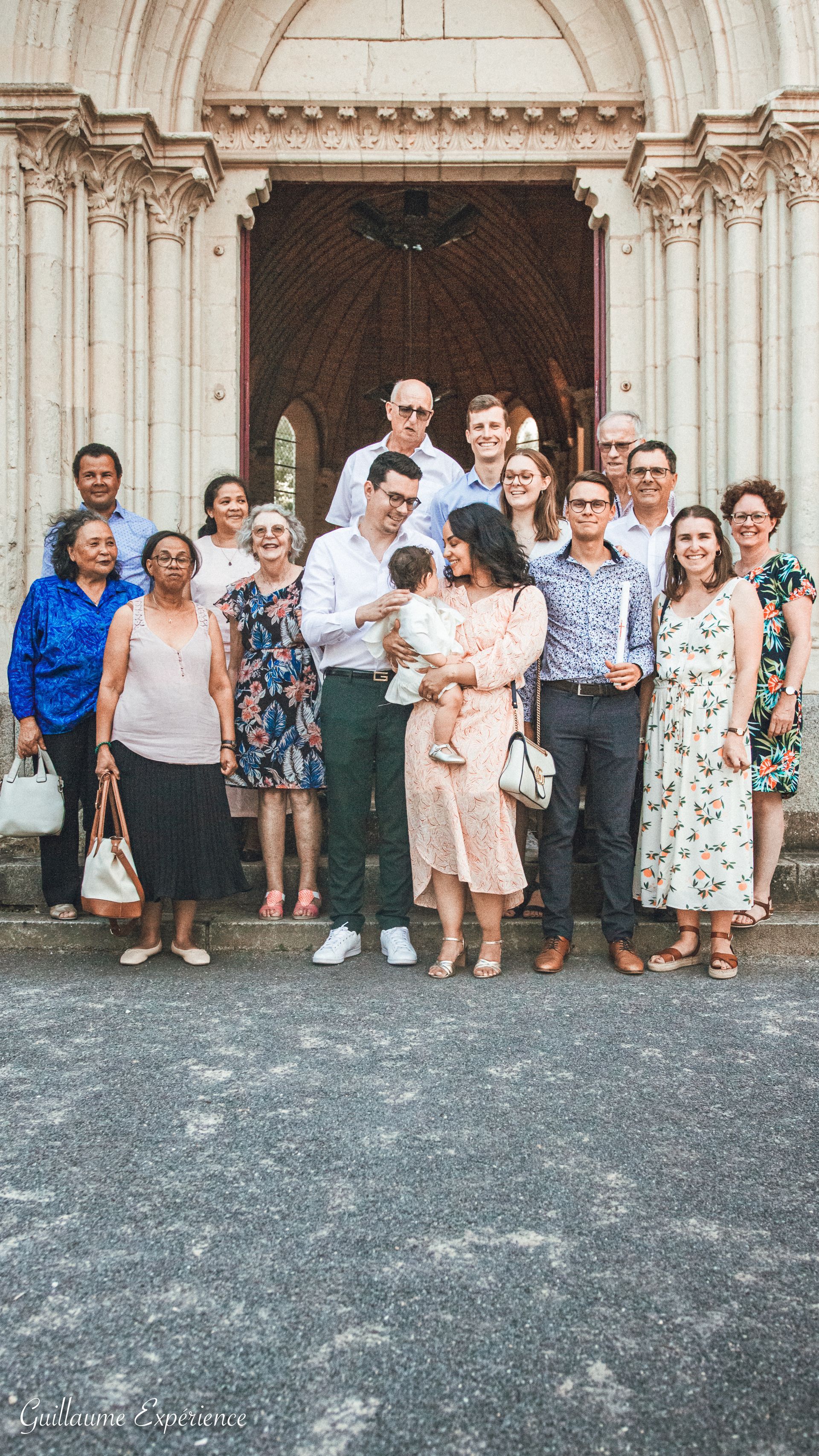 Un groupe de personnes pose pour une photo devant une église. Elles sourient.