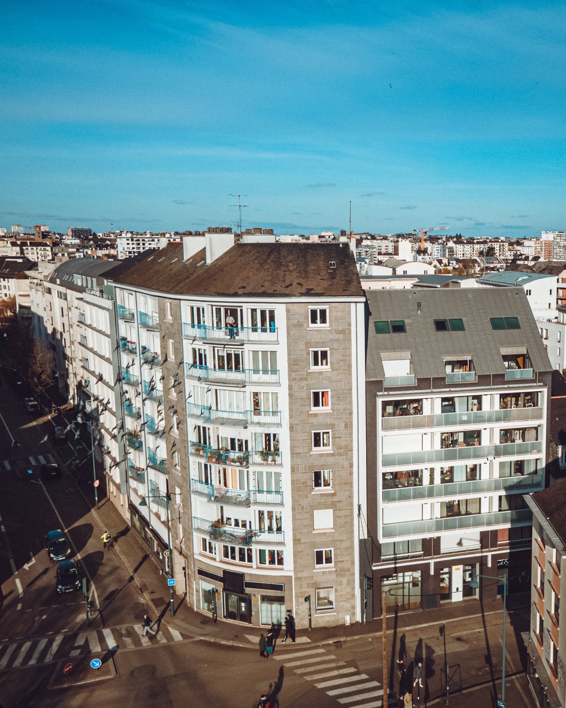 Immeubles d'appartements au coin d'une rue de la ville, ciel bleu au-dessus.