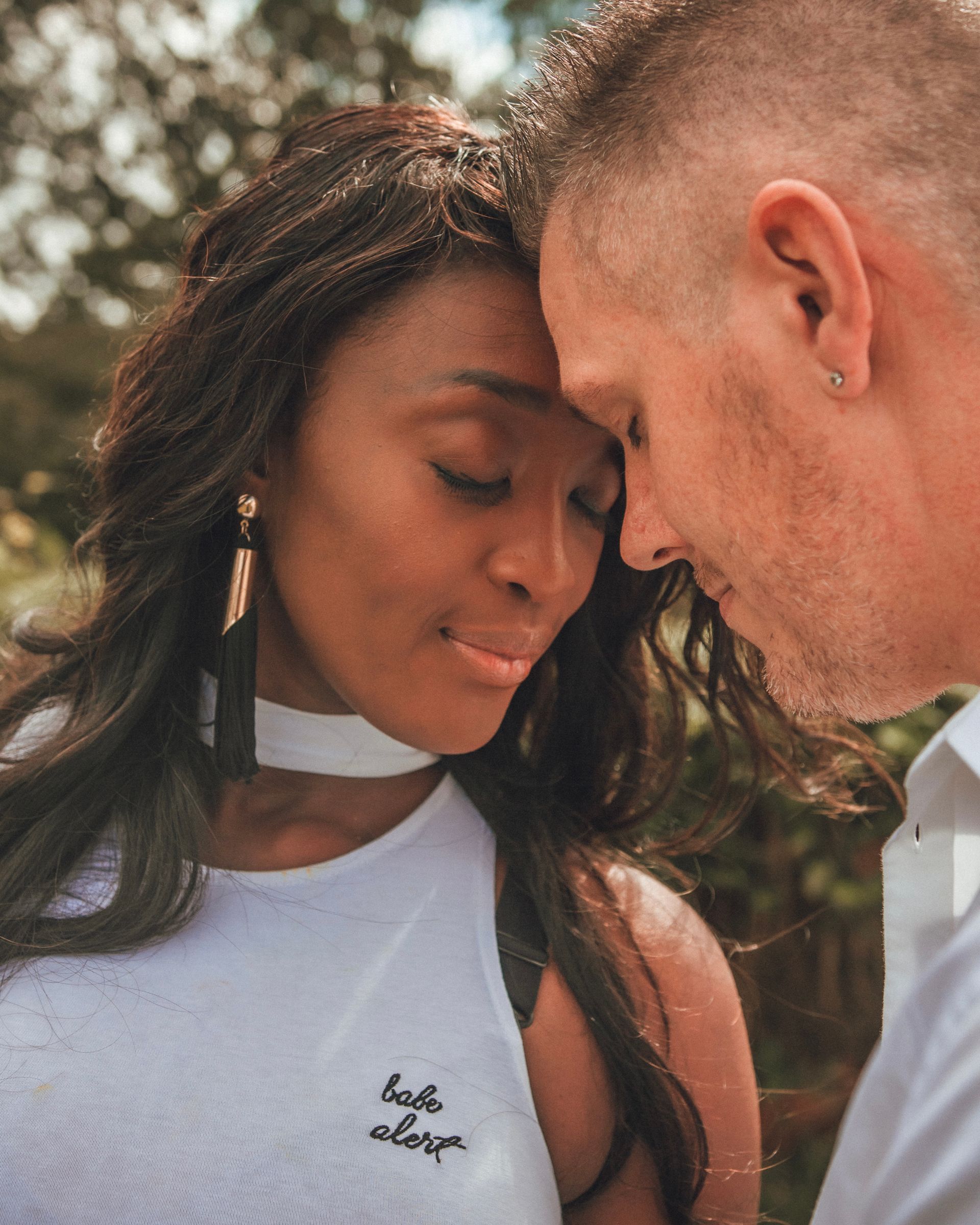 Couple enlacé, têtes jointes. Femme aux longs cheveux noirs, vêtue de blanc. Homme aux cheveux courts.