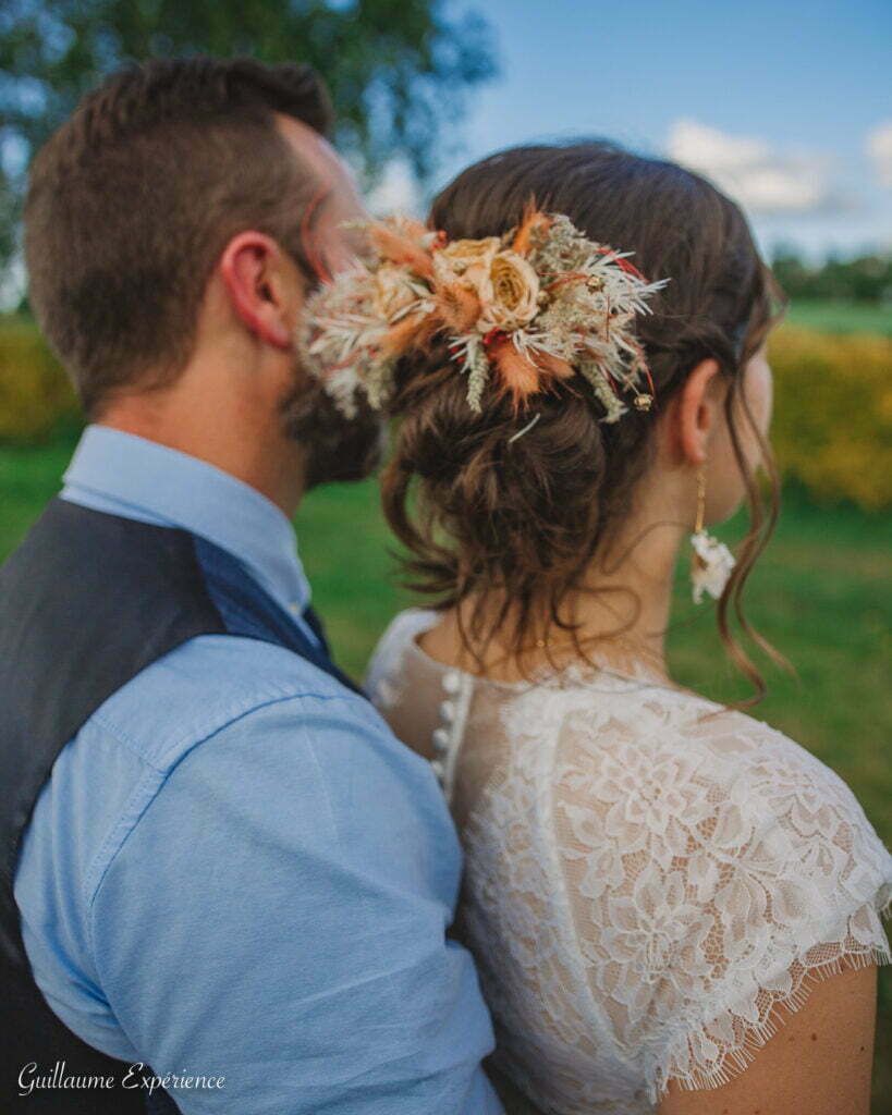 Couple, mariée avec postiche floral, marié, s'embrassant à l'extérieur.