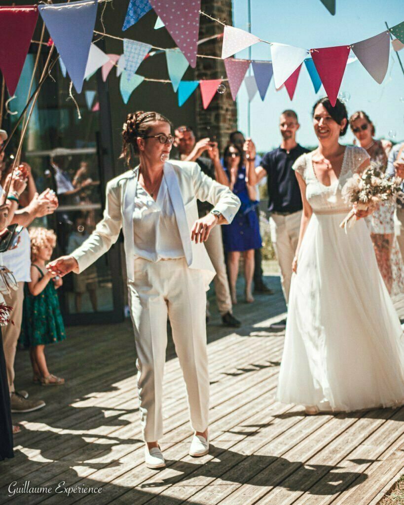 Deux mariées dansent pour célébrer leur mariage. Les invités arborent des cierges magiques sous des guirlandes colorées.