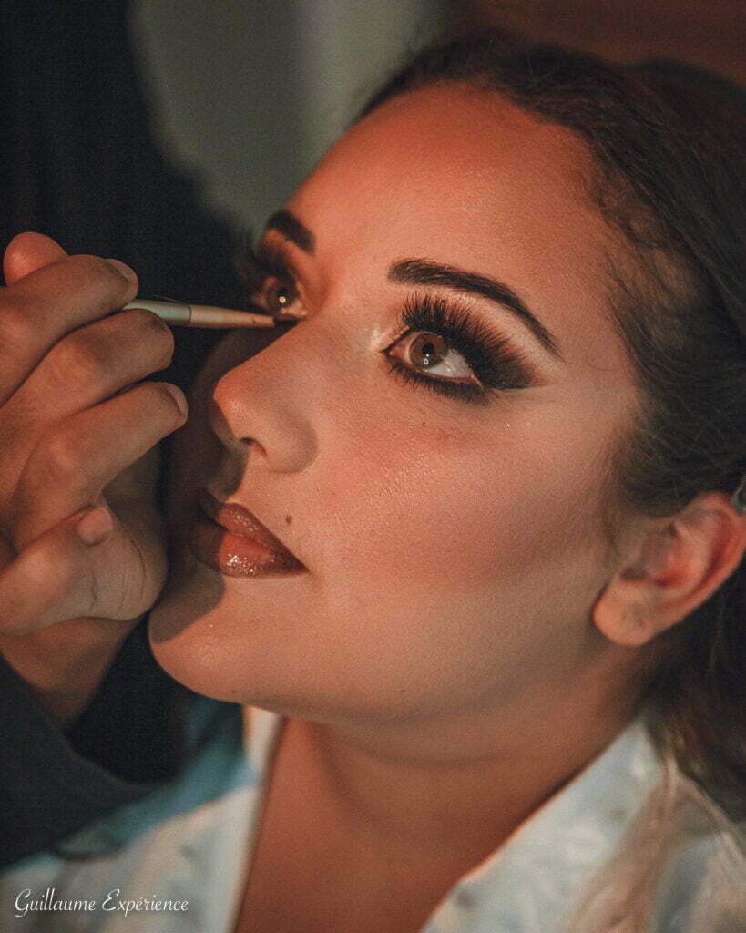 Une maquilleuse applique de l'eye-liner sur les yeux d'une femme. 