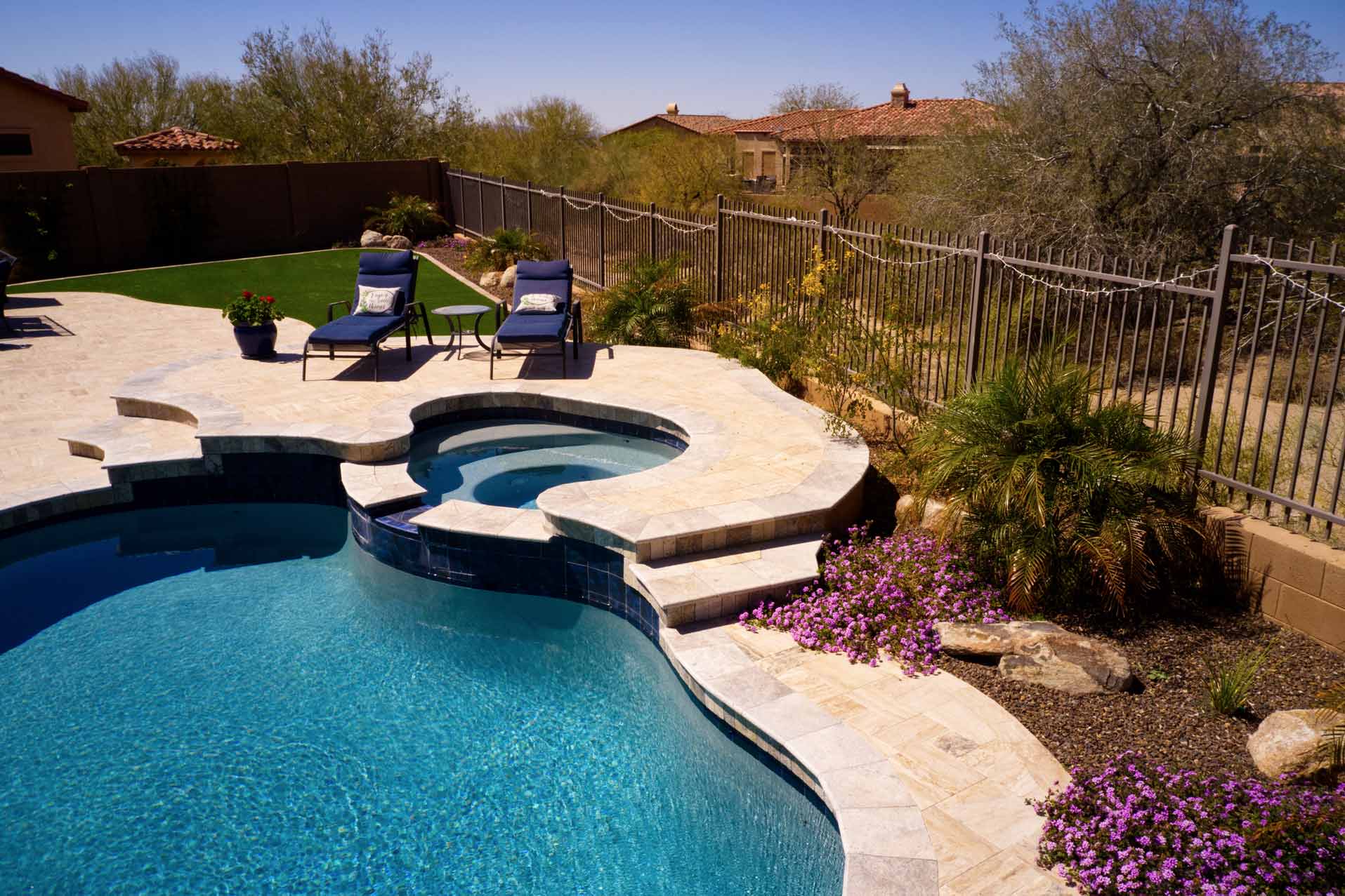 Une piscine avec margelles et terrasse en travertin