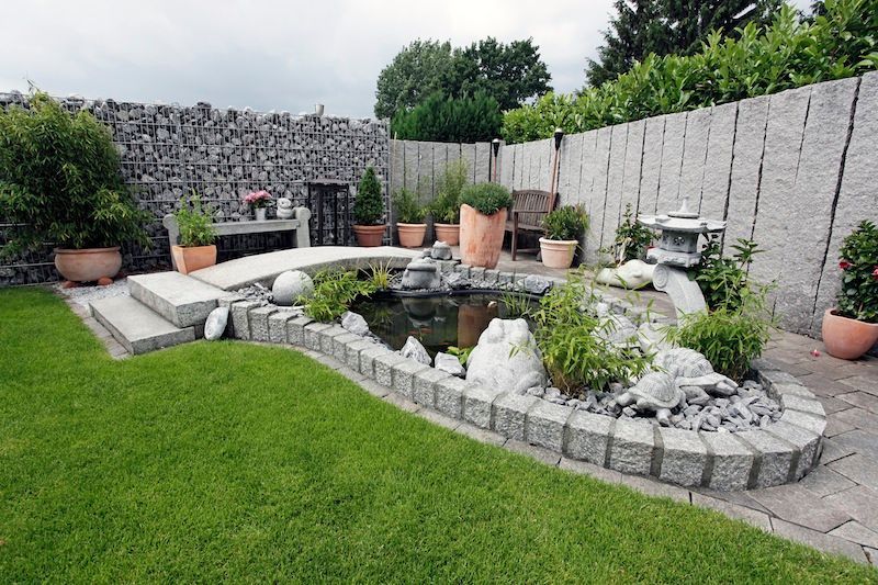 Ein Garten mit Teich und Steinmauer