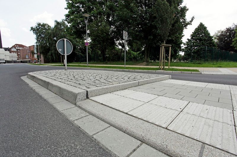 Eine Straßeninsel mit einem Fußgängerüberweg und Leitstreifen für Sehbehinderte