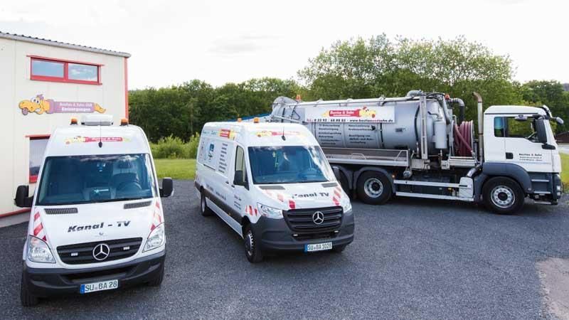 Drei Lieferwagen und ein LKW stehen vor einem Gebäude