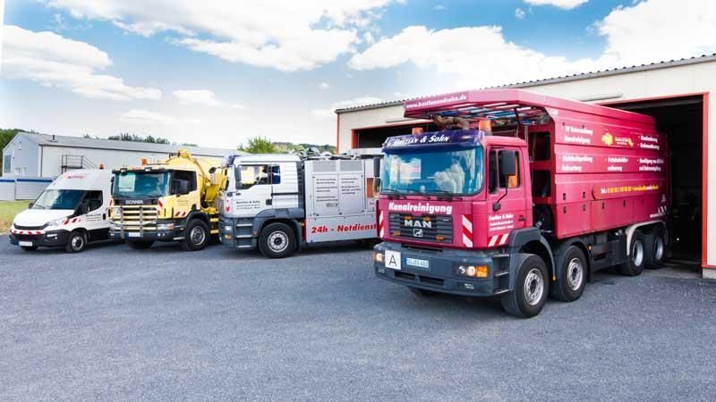 Eine Gruppe von Lastwagen parkt vor einer Garage.