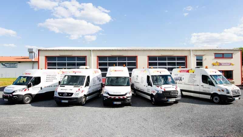 Eine Reihe weißer Lieferwagen, die vor einem Gebäude parken