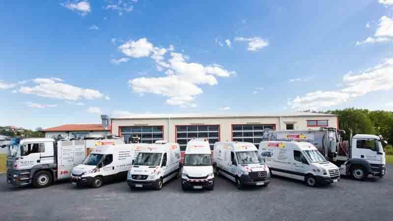 Eine Reihe weißer Lieferwagen parkt vor einem Gebäude.