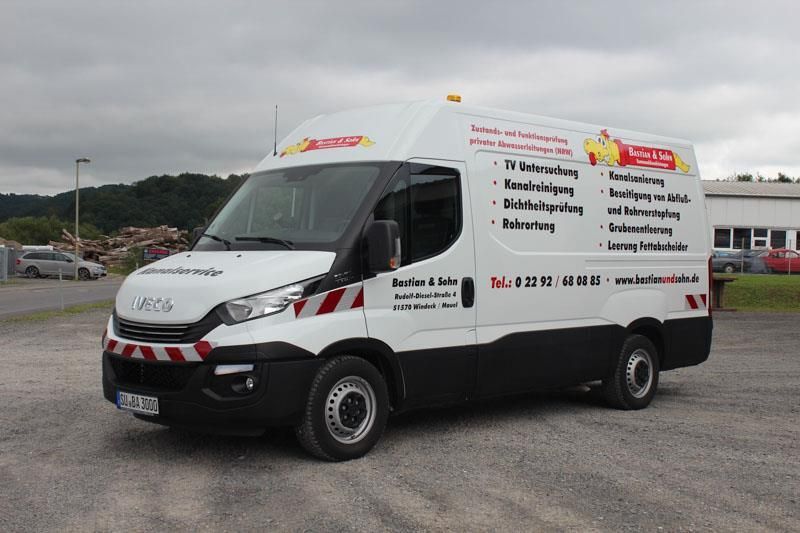 Ein weiß-schwarzer Lieferwagen steht auf einem Parkplatz