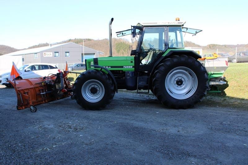 Ein grüner Traktor mit einem daran befestigten Schneepflug