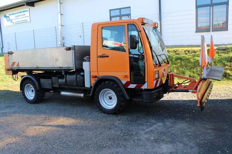 Ein orangefarbener LKW mit einem daran befestigten Schneepflug