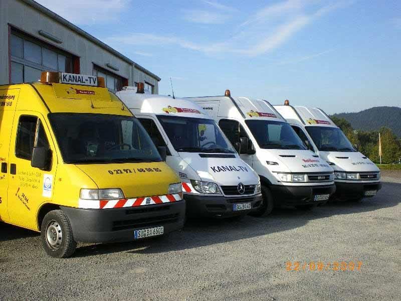 Eine Reihe gelber und weißer Lieferwagen steht vor einem Gebäude