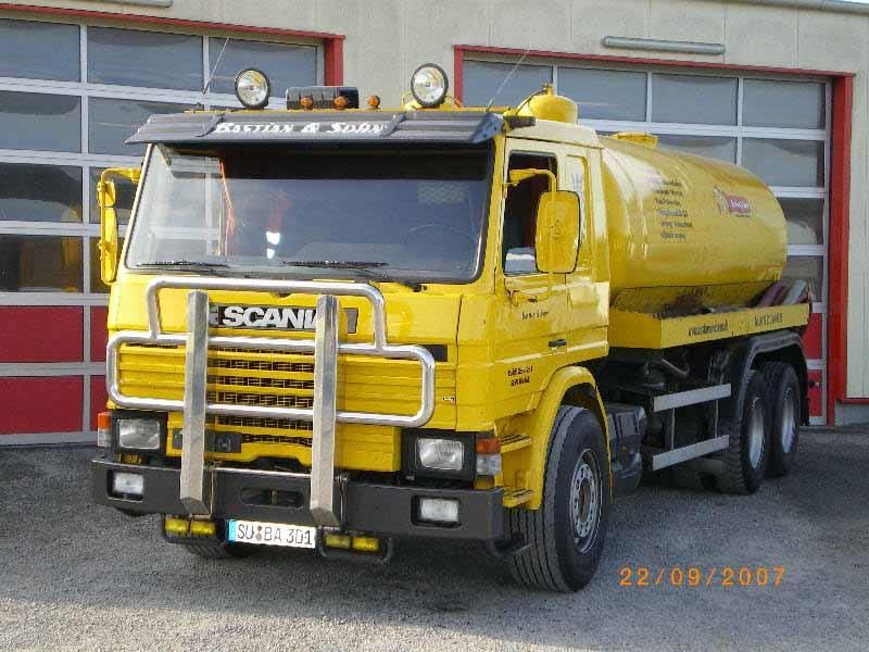 Ein gelber Scania-LKW steht vor einer Garage