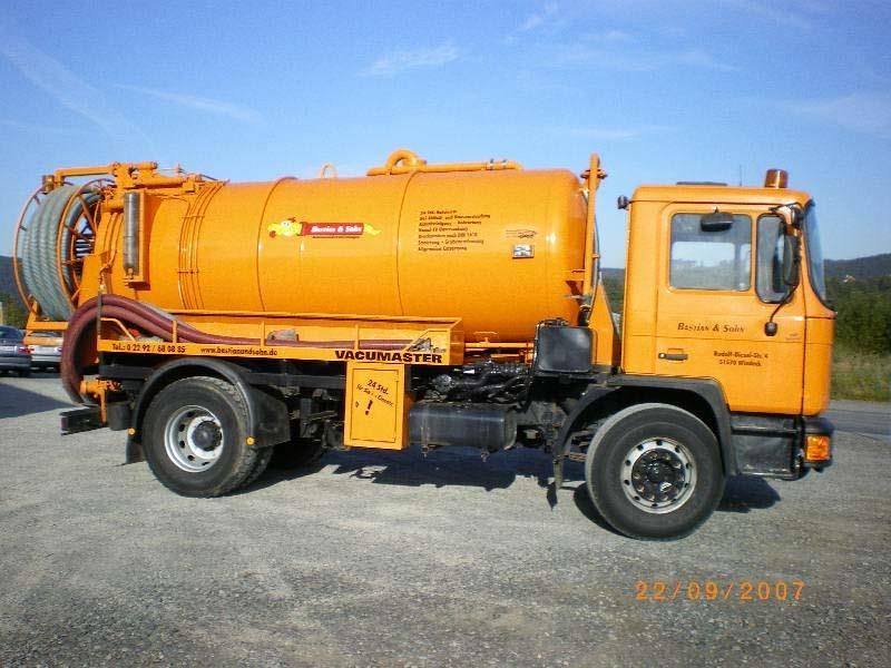 Ein orangefarbener Saugwagen steht am Straßenrand