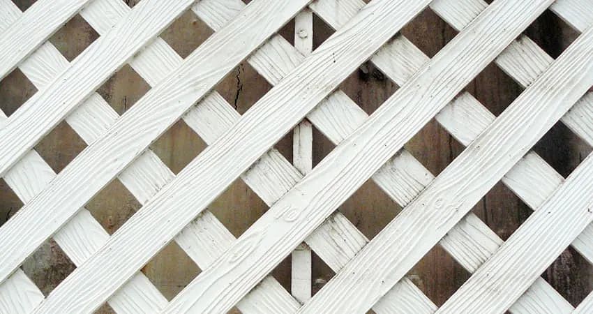 Un primer plano de una celosía blanca sobre una superficie de madera.