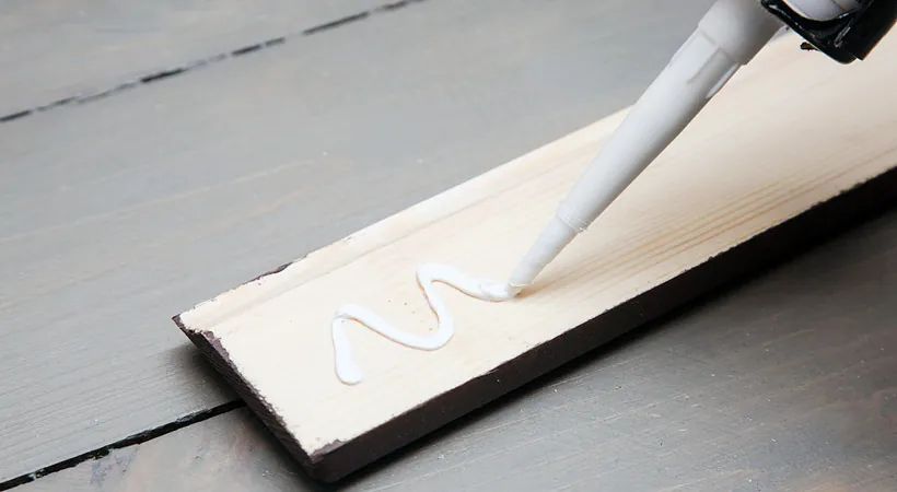 Una persona está aplicando pegamento a un trozo de madera.