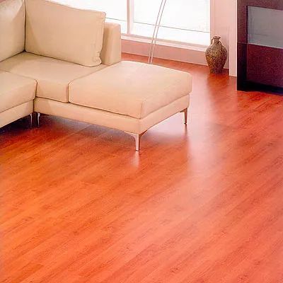 Una sala de estar con un sofá y una otomana sobre un piso de madera.