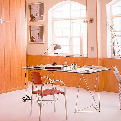 Un escritorio con una silla y una lámpara frente a una ventana.