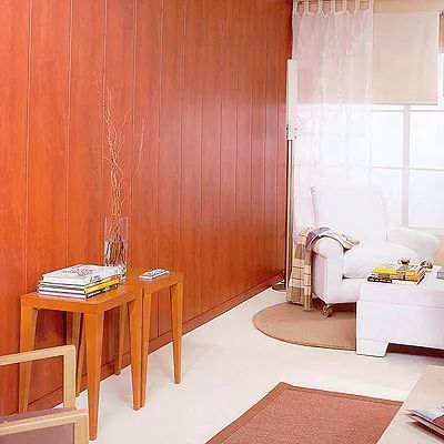 Una sala de estar con paredes revestidas de madera y una silla blanca.