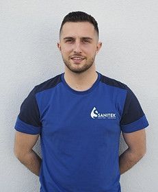 Ein Mann mit Bart trägt ein blau-schwarzes T-Shirt. Sanitek GmbH