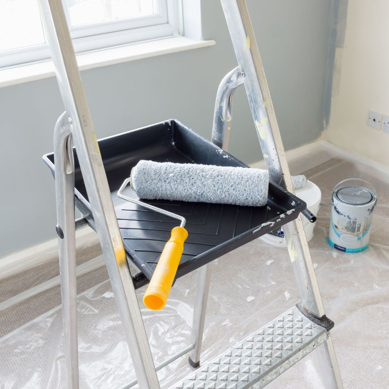 Rouleau et bac à peinture posés sur une échelle