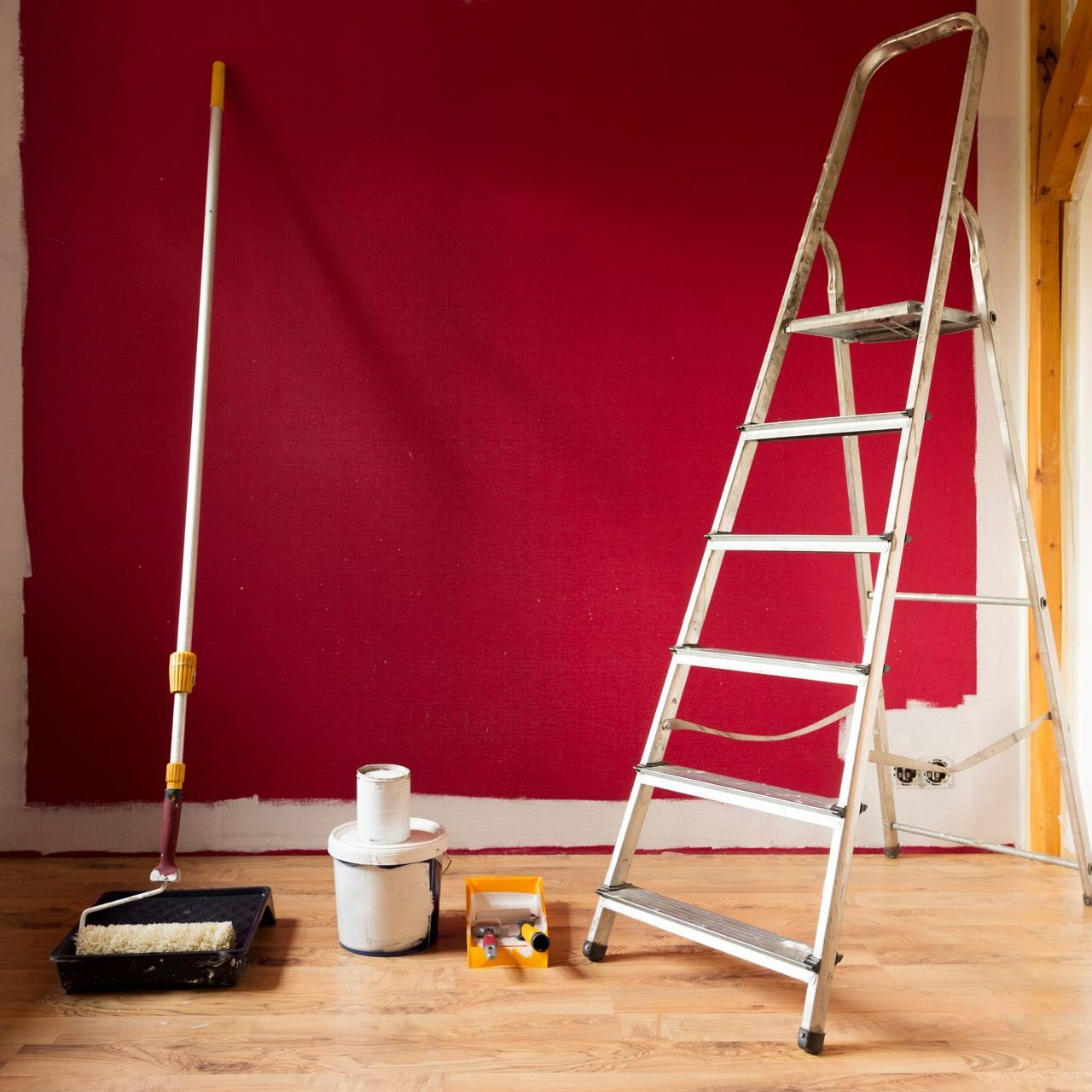 Mur intérieur peint en rouge avec échelle et matériel de peinture