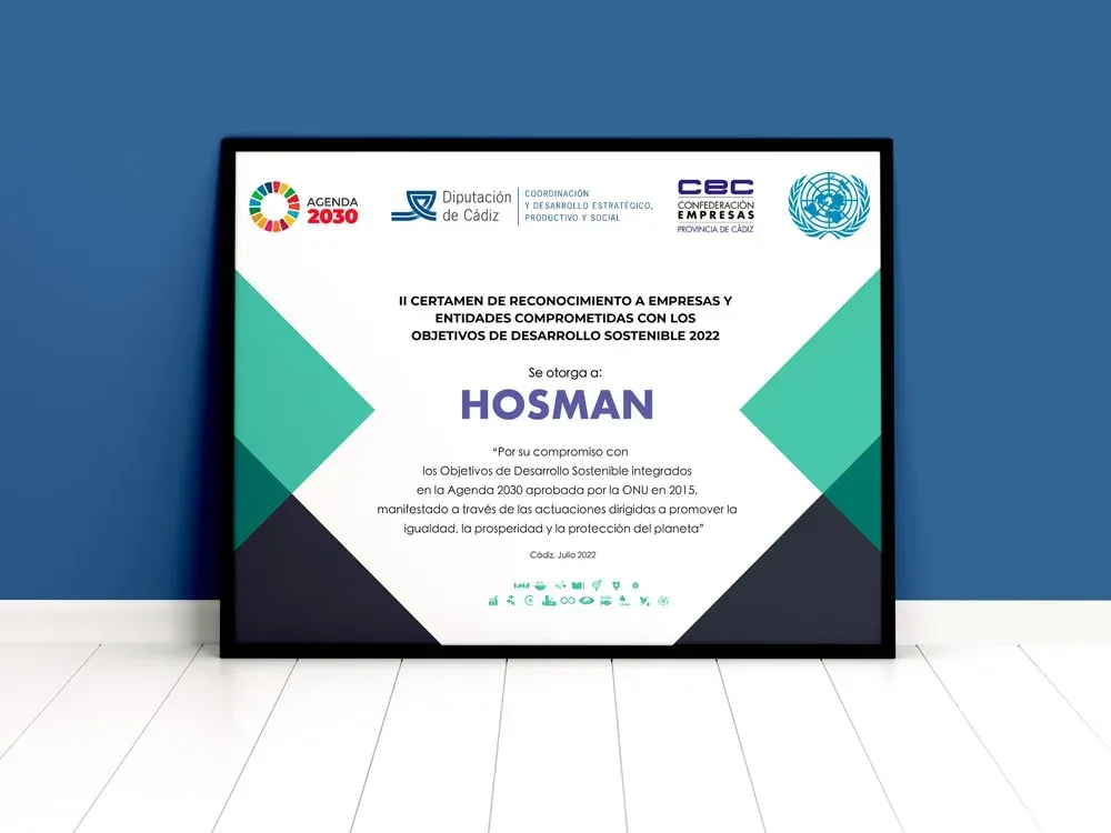 Un certificado enmarcado se encuentra sobre un piso de madera frente a una pared azul.