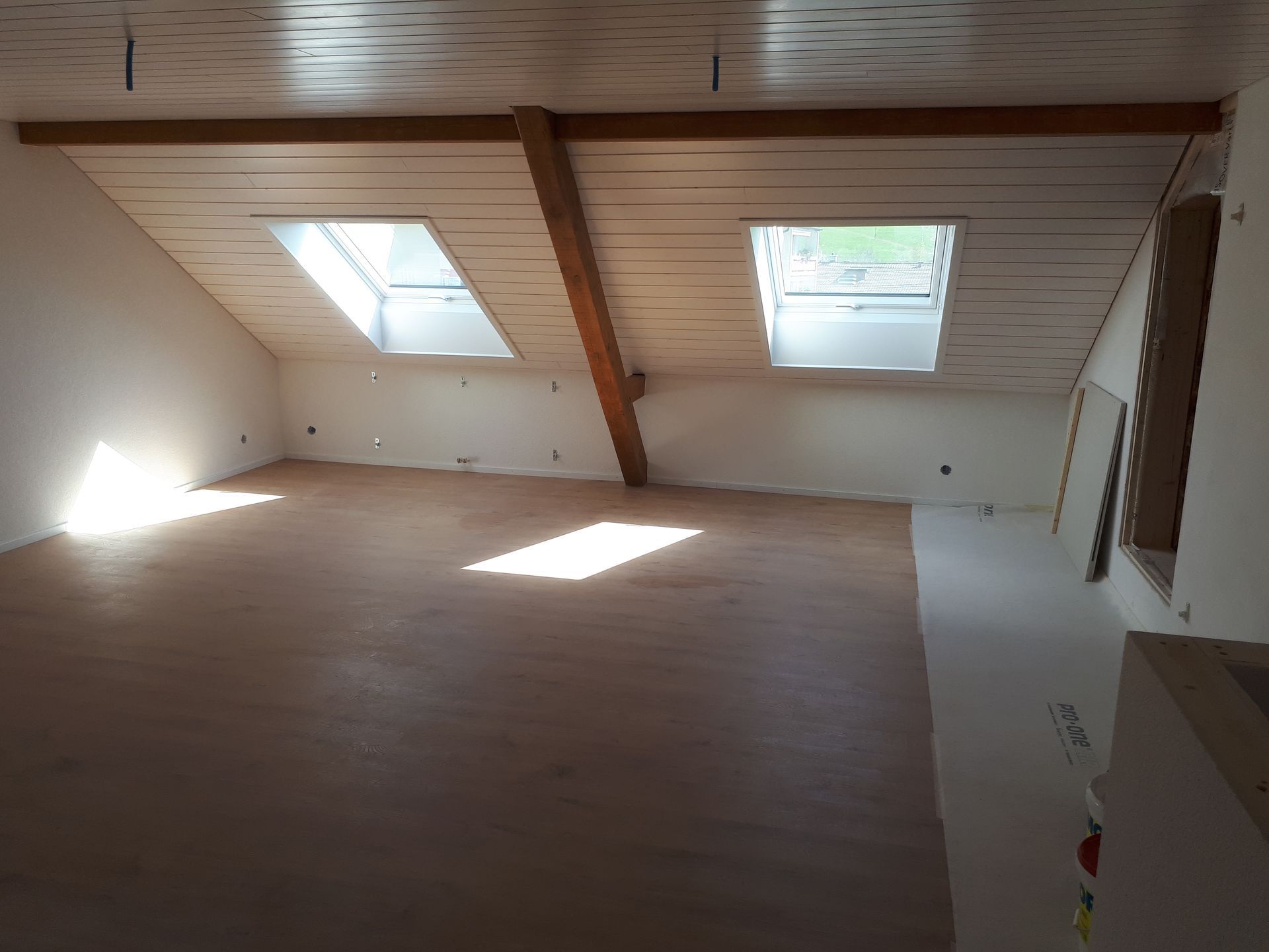 Balcon en bois avec balustrade courbée donnant sur un espace gazonné.